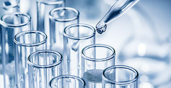 Drops of liquid being dispensed into a test tube from a pipette